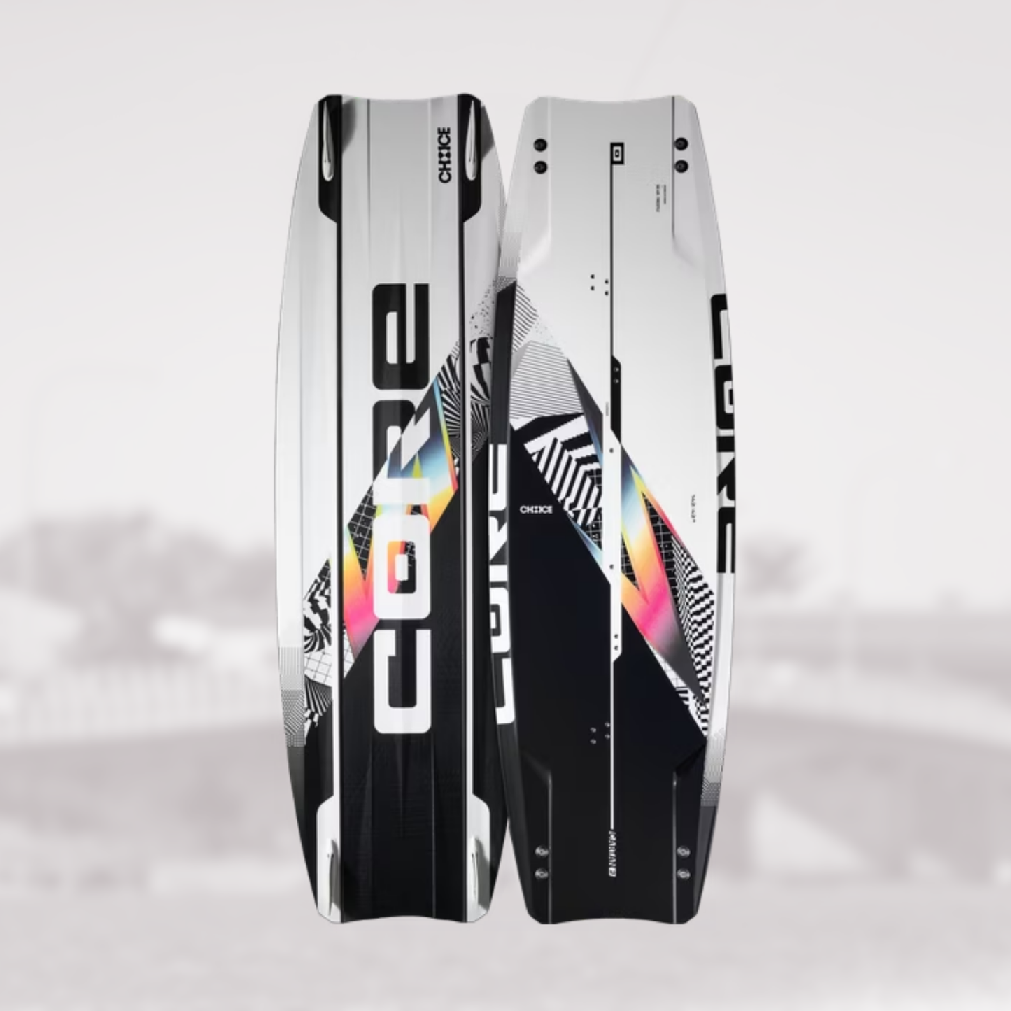 Two kiteboards shown upright against a light gray background, displaying both the topsheet and the bottomsheet views. The boards feature a white, black, and gray geometric pattern with a prominent holographic rainbow graphic running diagonally.